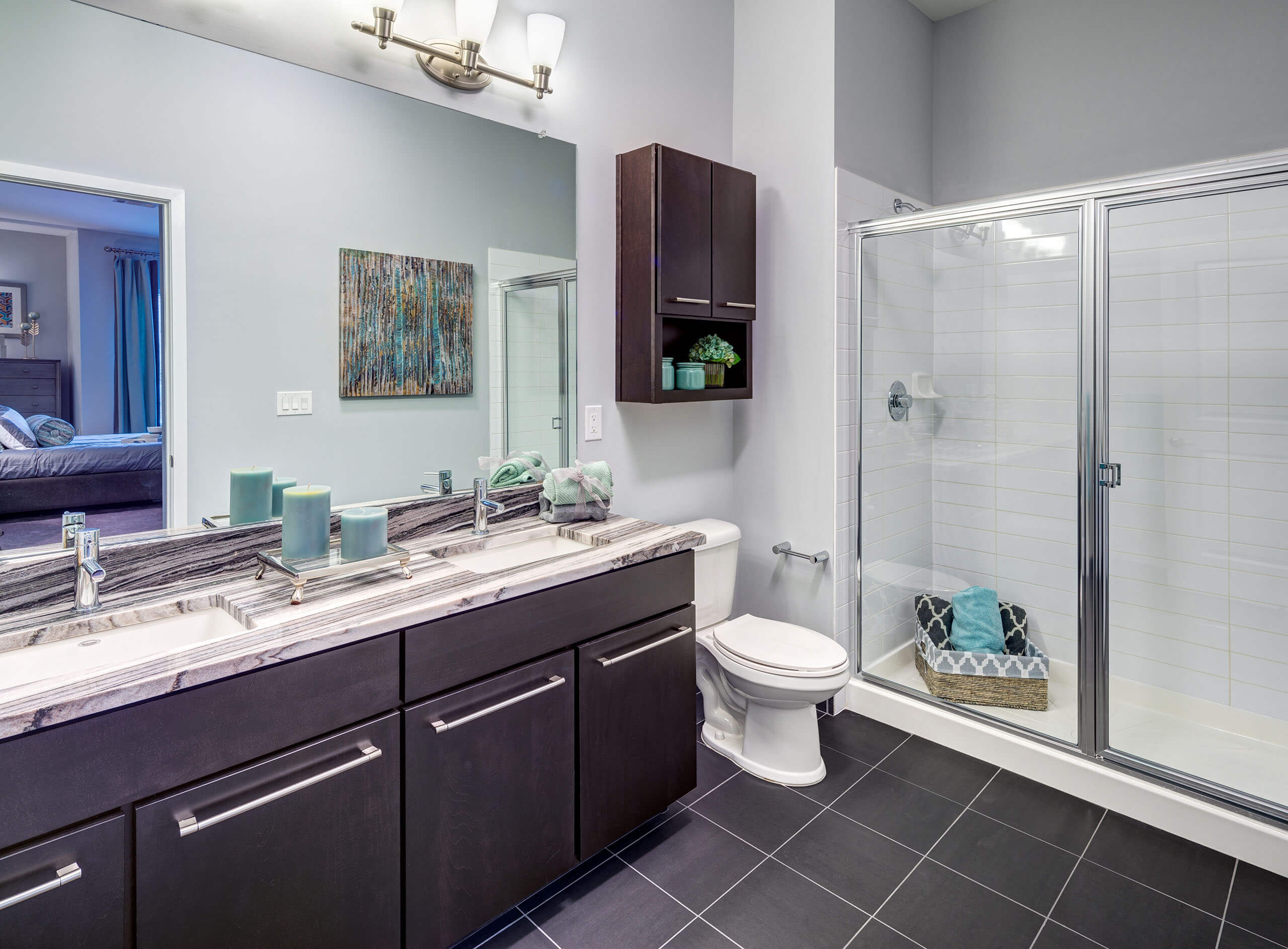 Bathroom with a dual sink vanity, tile flooring, and a large glass enclosed shower